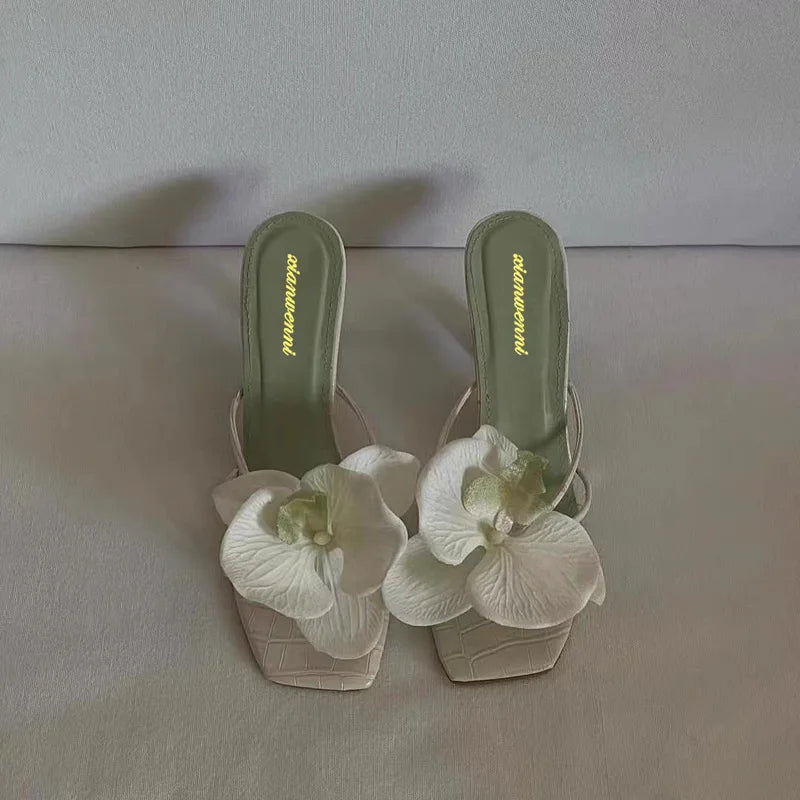 Stunning green high heels adorned with a beautiful white flower accent, perfect for adding a pop of color to any outfit.