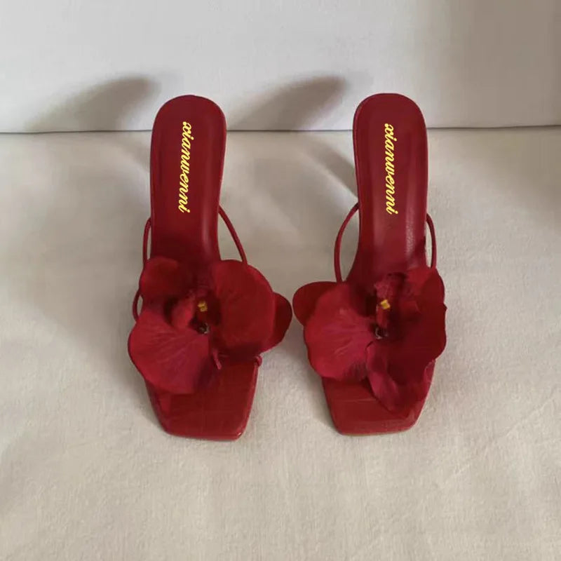 Eye-catching red high heels featuring a stunning white flower accent, perfect for making a bold fashion statement.